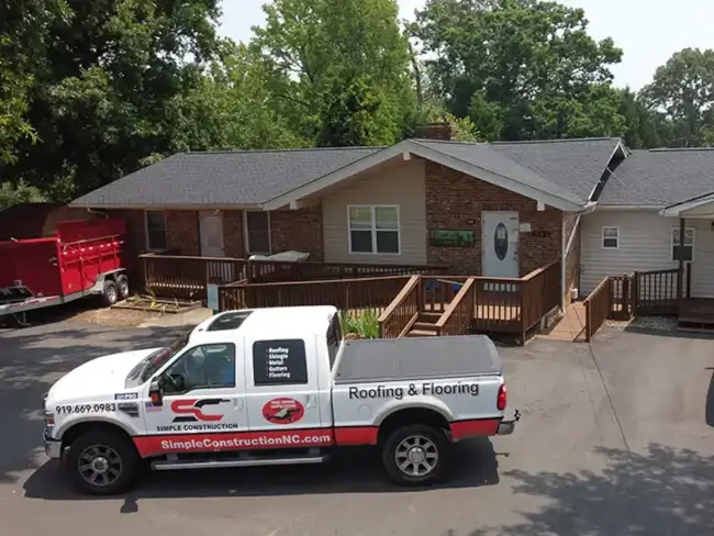 Simple Construction work pickup truck parked in front of a long residential home they recently installed new gray shingles on