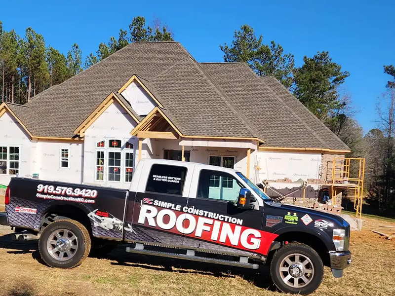 Top view of Simple Construction workers installing new gray shingles on a large residential roof
