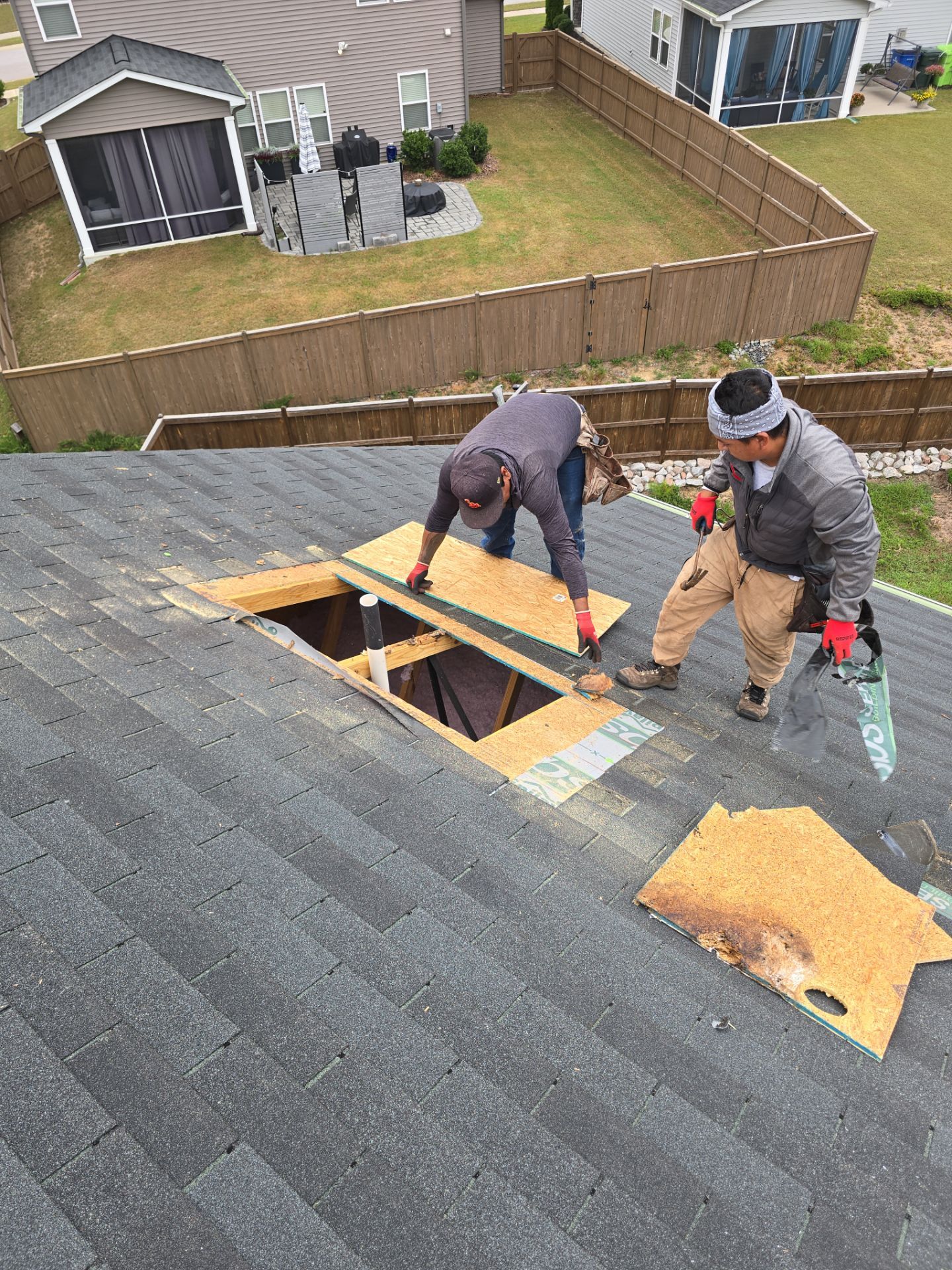 Crew installing plywood over large roof hole Raleigh NC