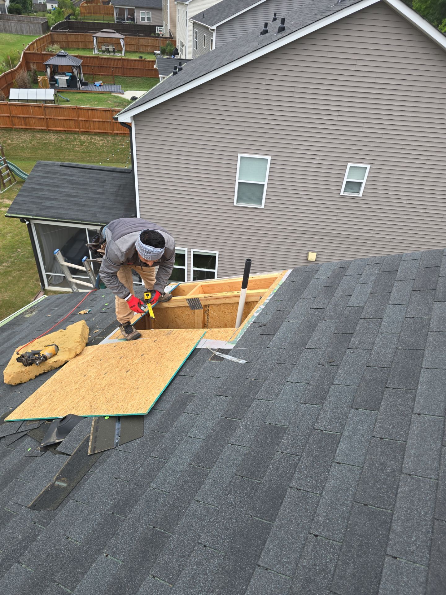 Worker securing plywood patch on damaged roof Raleigh NC