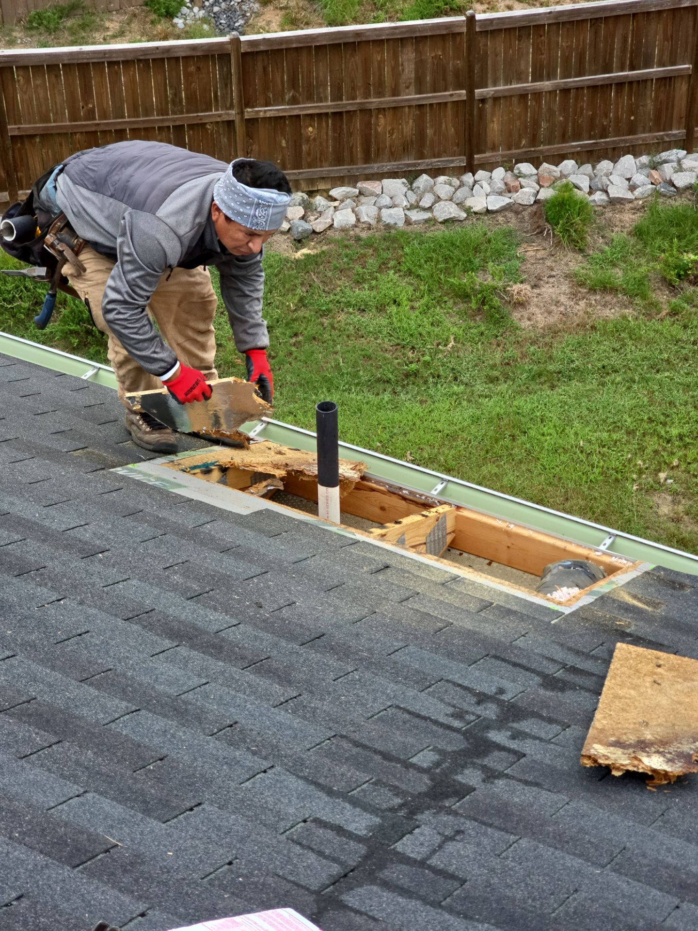 Roofer prying shingles around roof hole for repair Raleigh NC