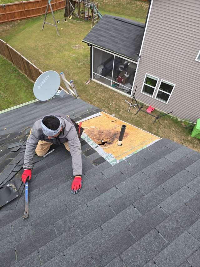 Worker hammering nails into plywood roof patch Raleigh NC