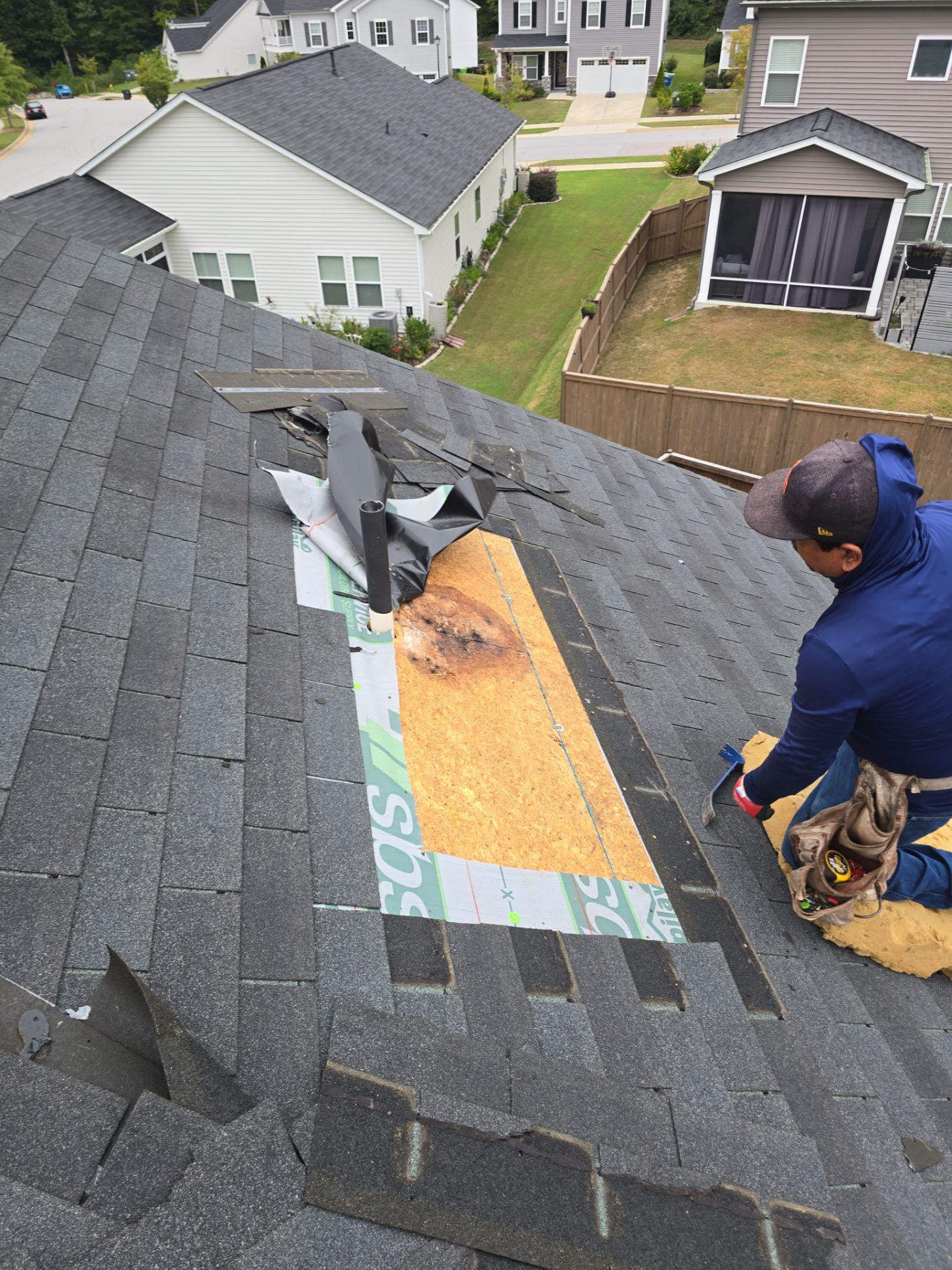 Worker installing shingle patch over damaged roof Raleigh NC